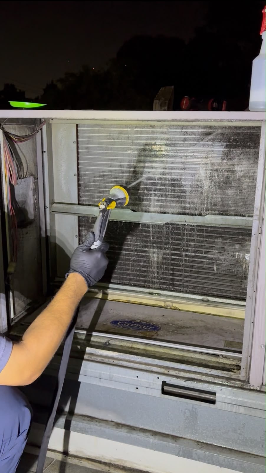 Technician cleaning the evaporator coil inside a Carrier rooftop HVAC unit at a Des Plaines restaurant