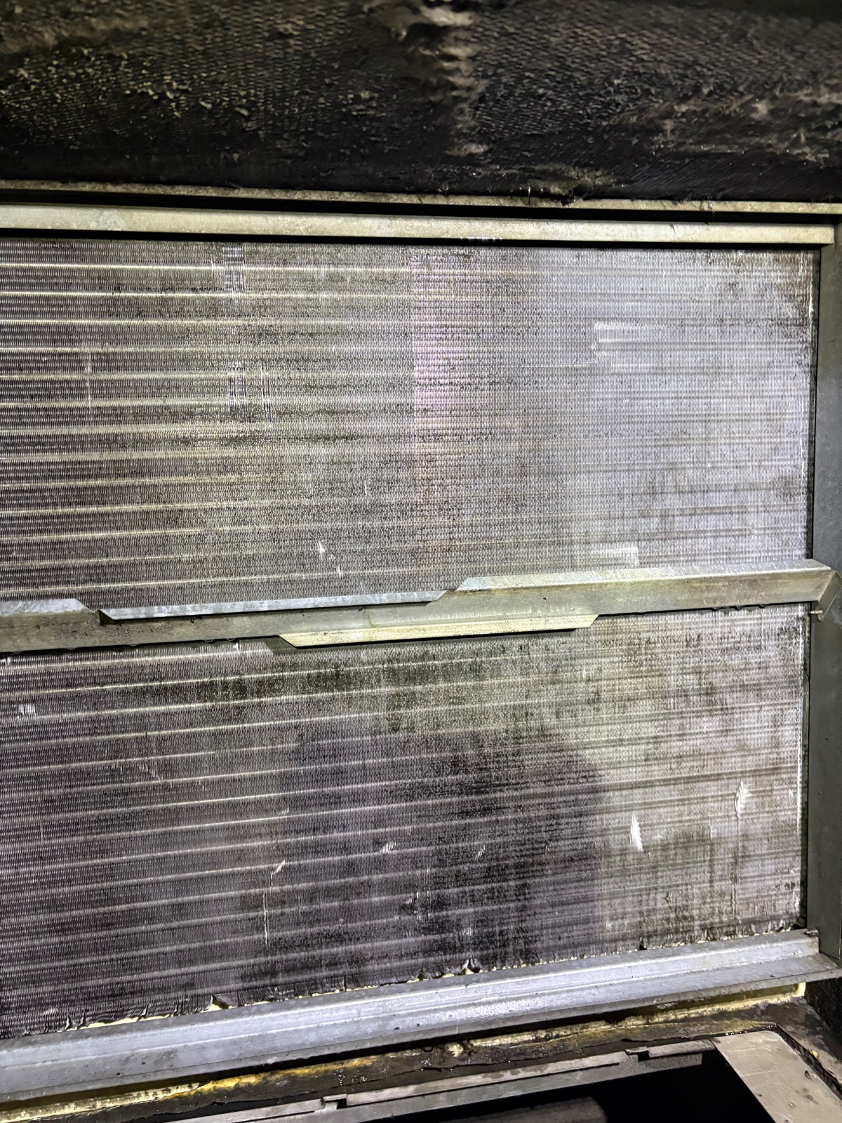 Grease, dust, and debris restricting airflow through the evaporator coil inside a Carrier rooftop HVAC unit
