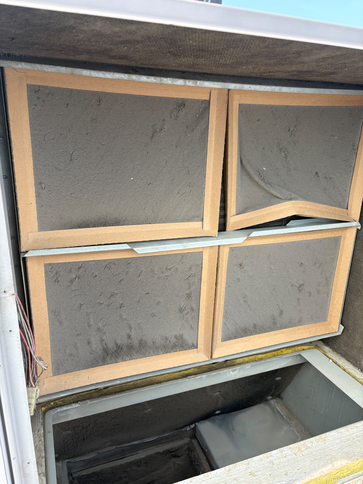 Heavily clogged air filters inside a Carrier rooftop HVAC unit at Fit and Fight Gym